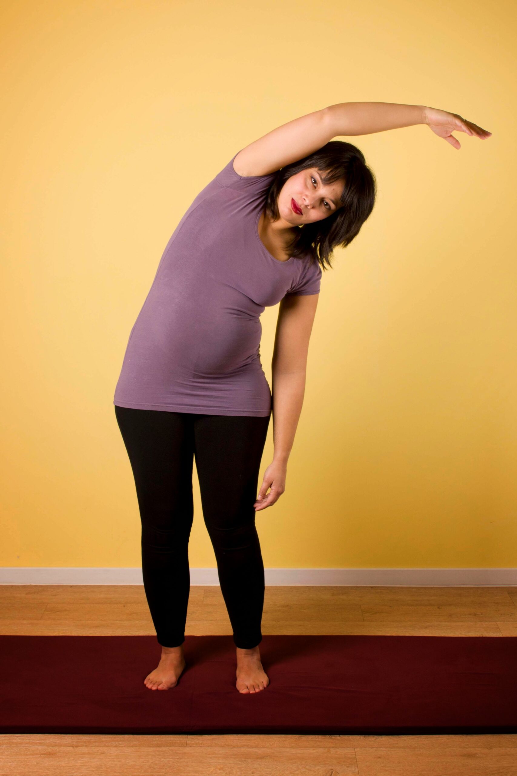 Zwangere vrouw doet de halve maan houding voor zwangerschapsyoga