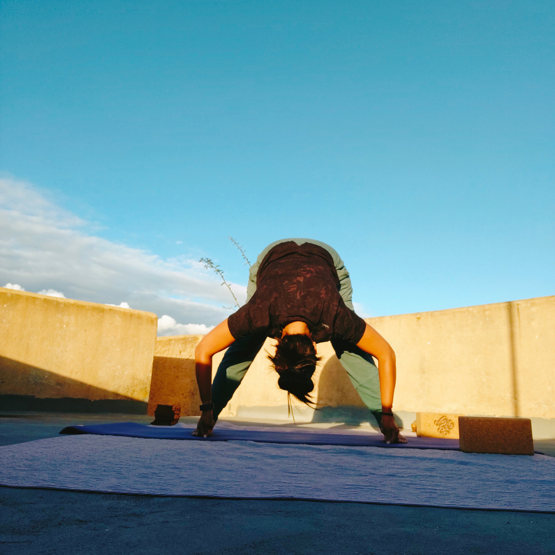 Pamela van Yogarve in yoga houding gedraaide zittende twist op een rots boven een rivier in midden Portugal